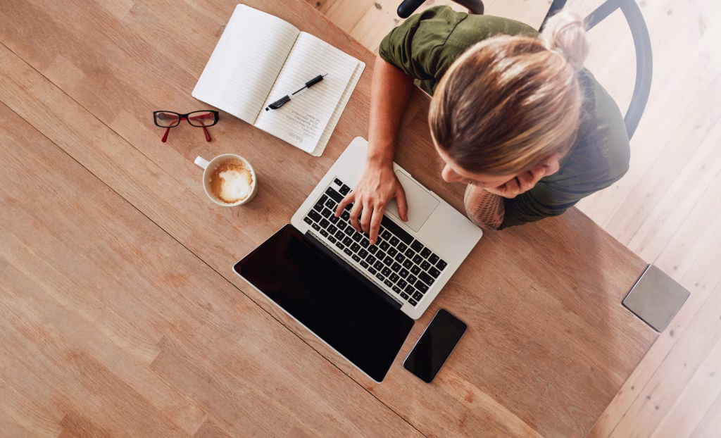 Women sitting at a table surfing the internet on her computer.
